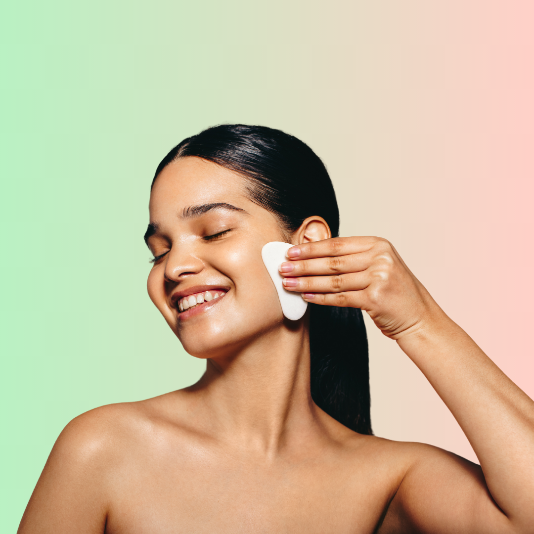 una mujer usando la gua sha en su cara.